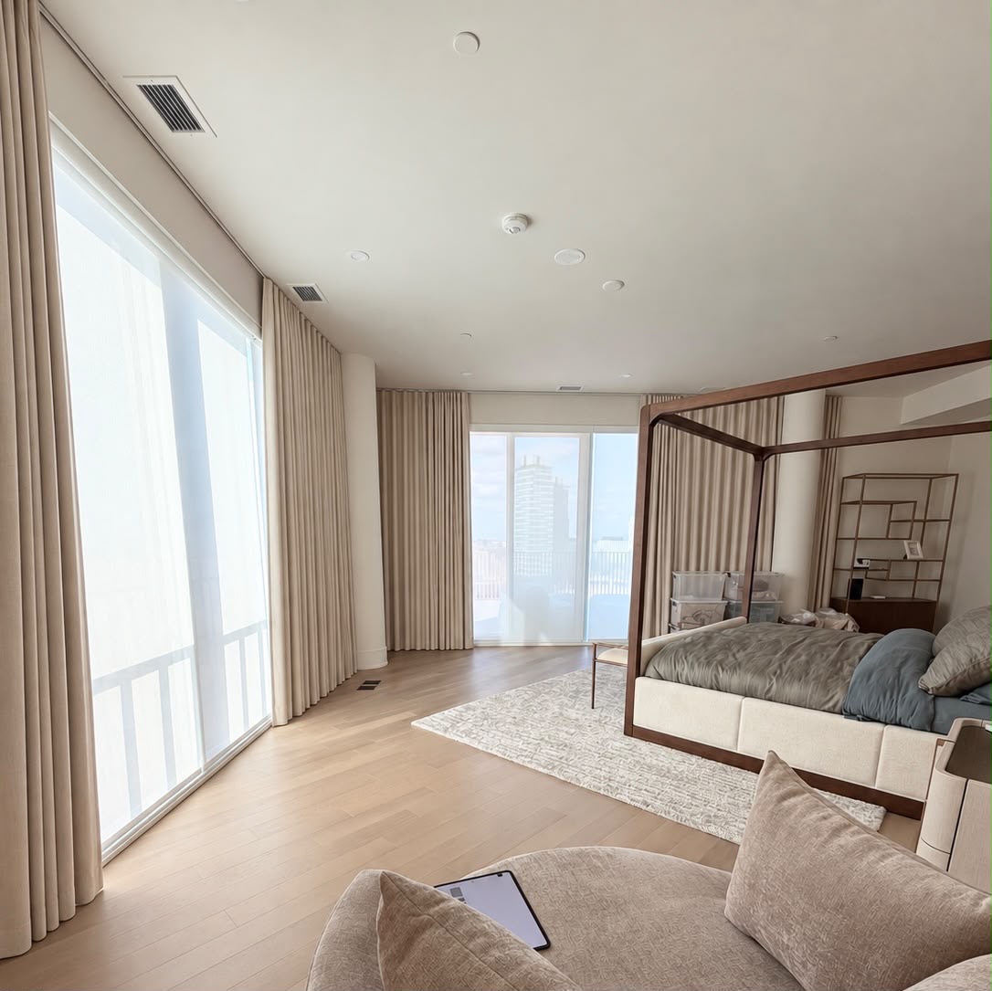 Light-filtering roller shades and ivory drapery in a contemporary bedroom